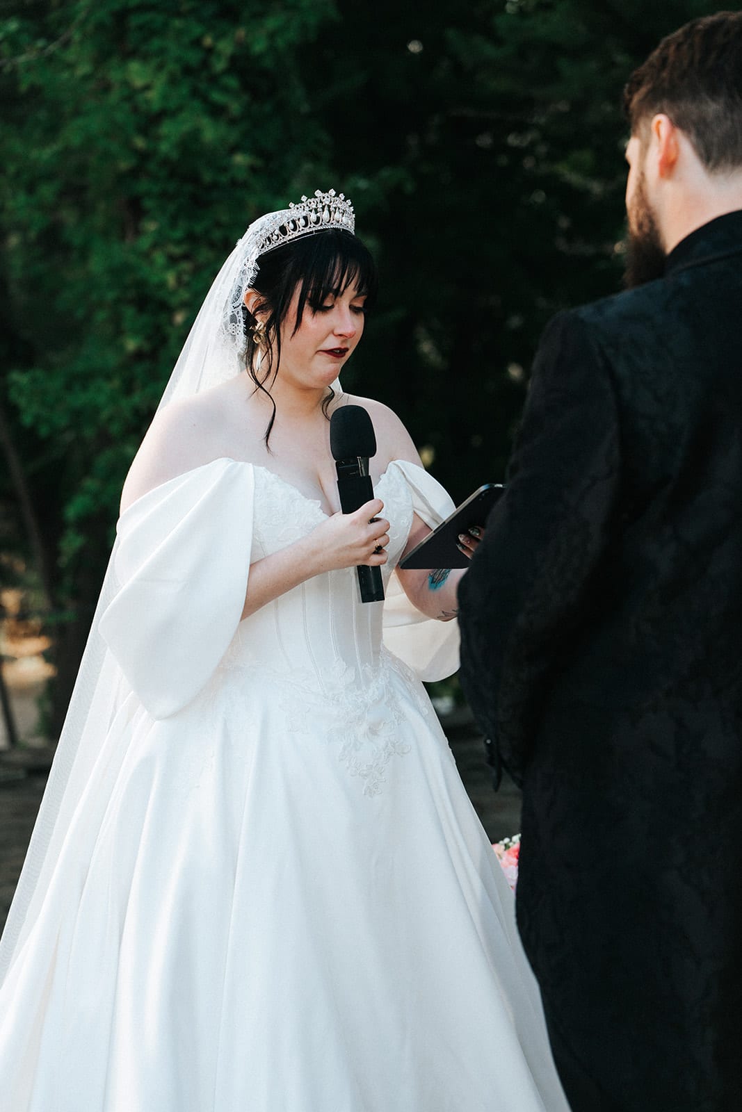 Porscha reading her vows to Jordan beneath the floral arch