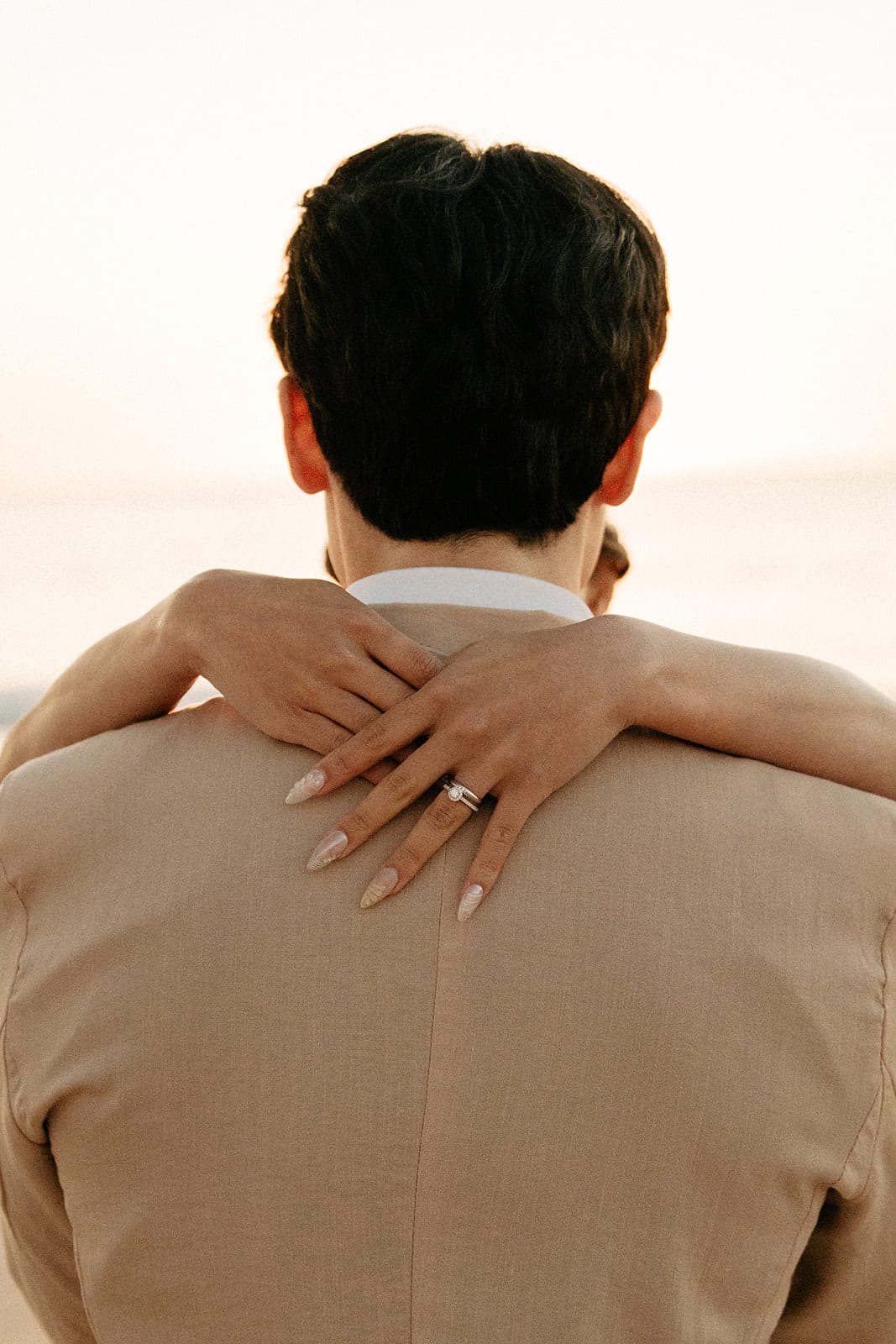 Sayuri’s hands clasped around Shuto’s back, her ring catching the light