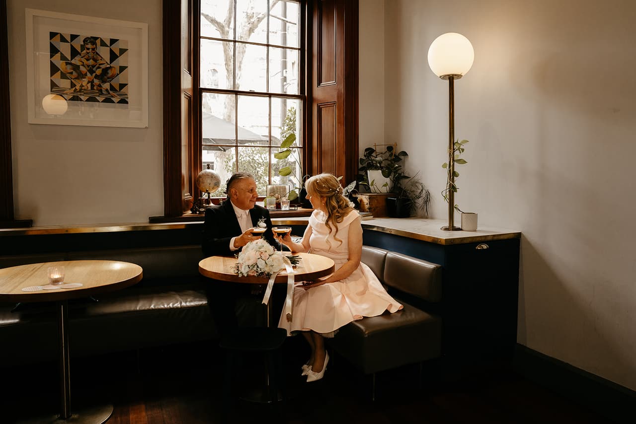 Terrie and Jon sitting close in a booth at Treasury 1860 beside a glowing lamp
