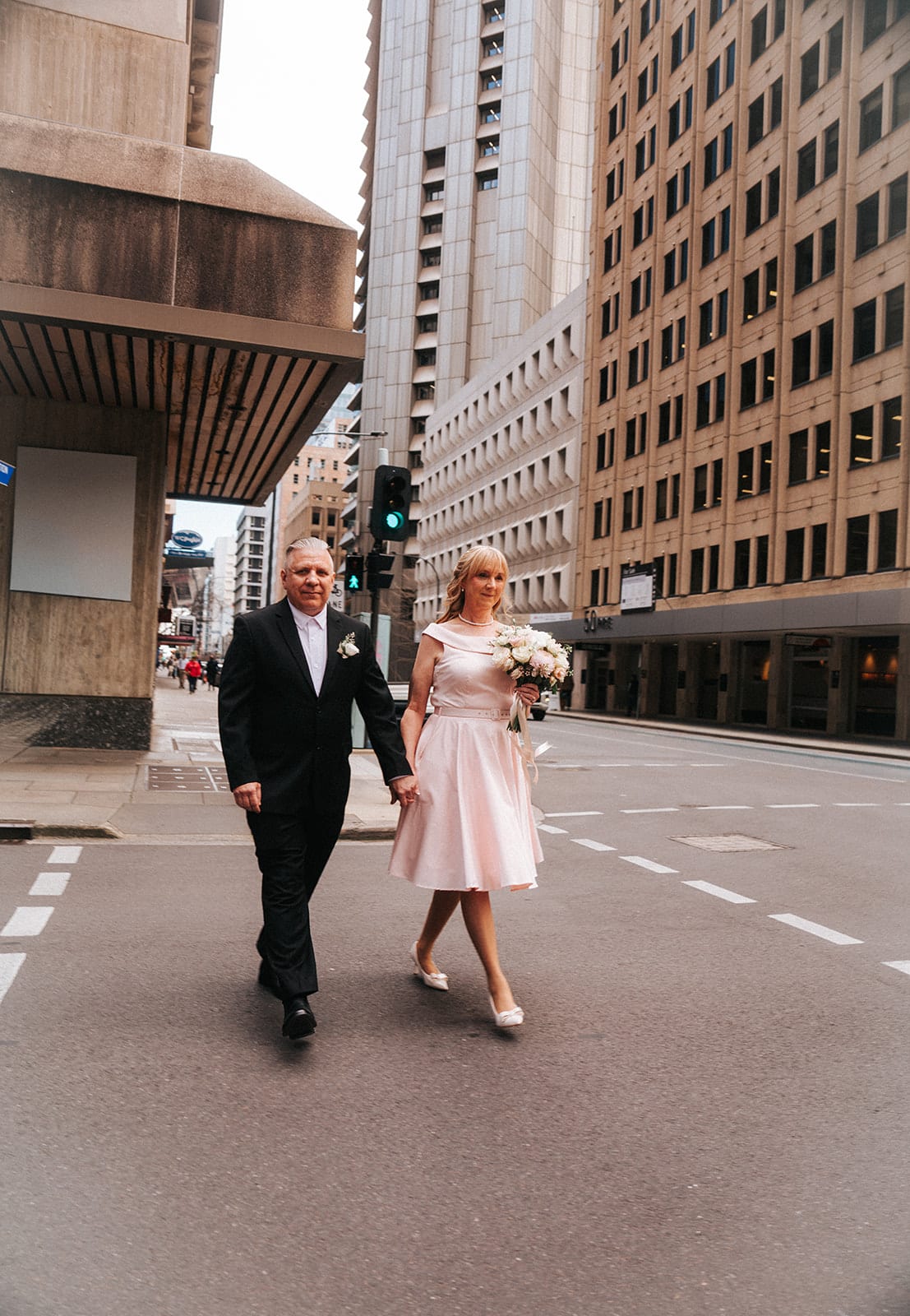 Terrie and Jon walking down a city street between tall buildings
