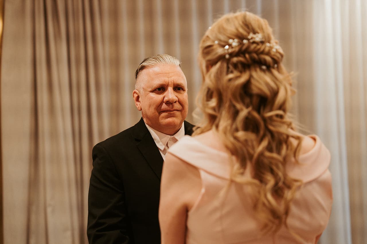Jon smiling at Terrie during the ceremony, seen over her shoulder and the pearl pins in her hair