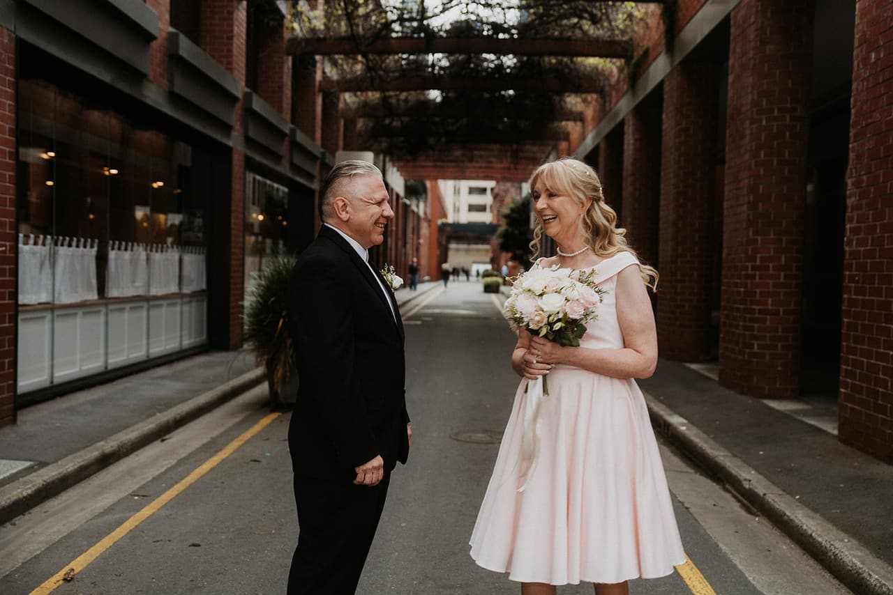 Terrie and Jon facing each other in a laneway under hanging greenery