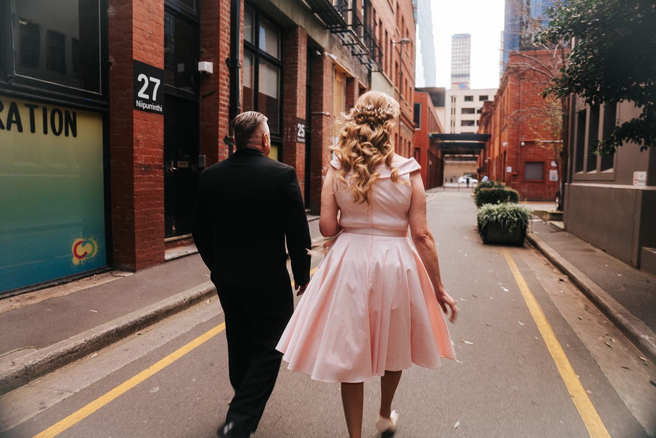 Terrie and Jon walking away down a narrow laneway between red brick buildings