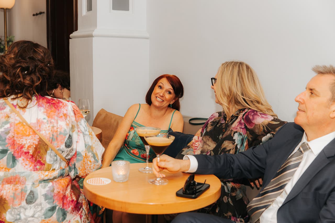Guests laughing around a small table with espresso martinis