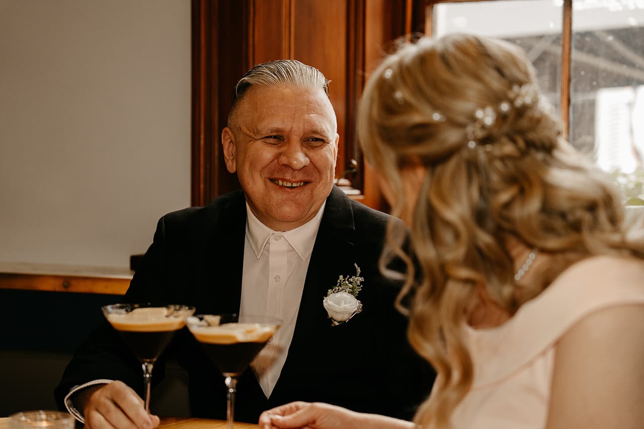 Jon laughing with Terrie over two espresso martinis at a table by the window