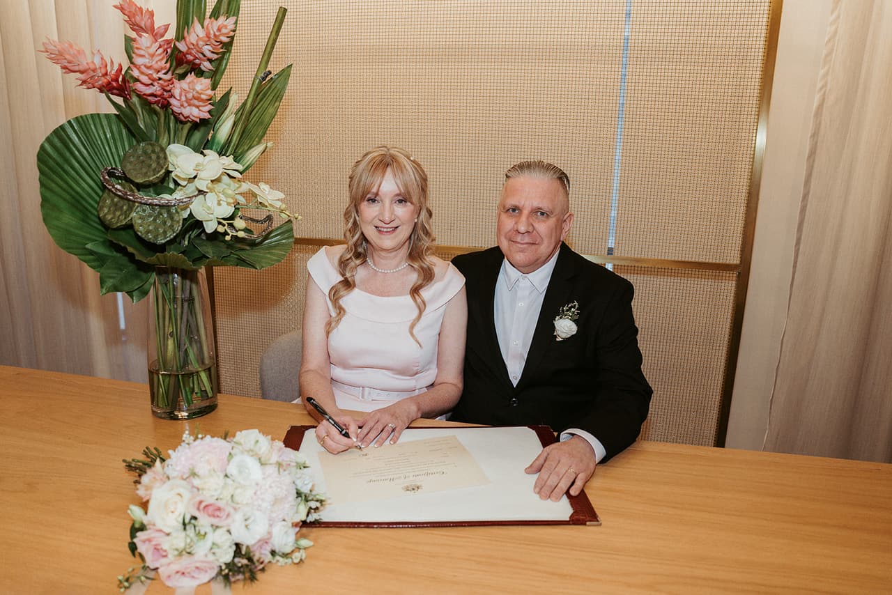 Terrie and Jon smiling at the table as they sign the register