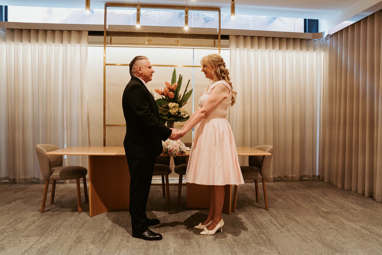 Terrie and Jon facing each other during their ceremony in the timber-lined registry room