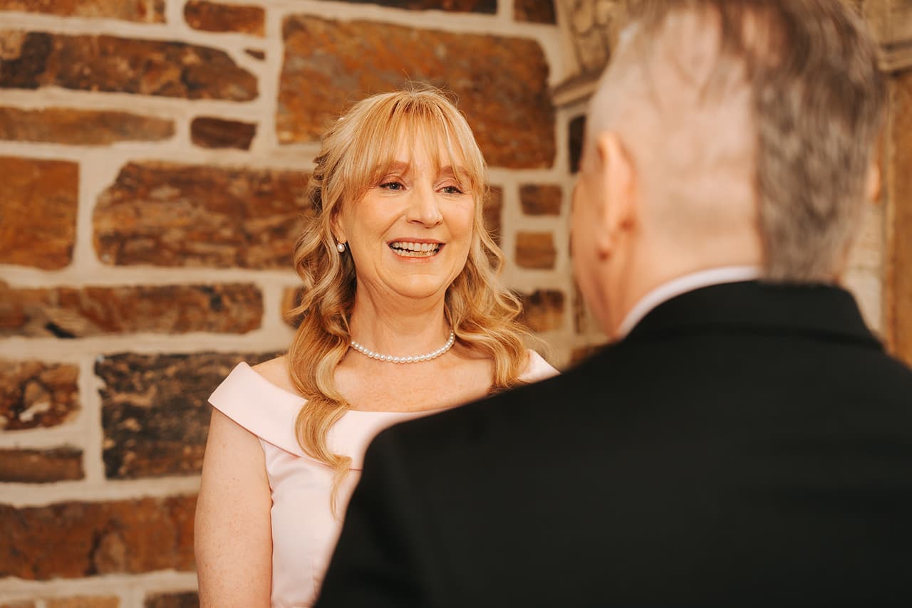 Terrie smiling at Jon in front of a rough sandstone wall