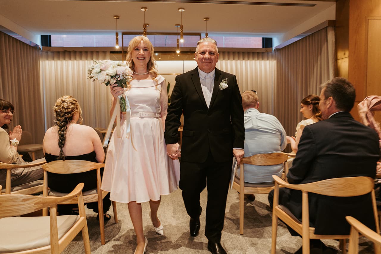 Terrie and Jon walking back down the aisle hand in hand as their guests clap